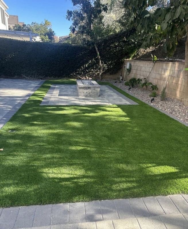 Paver patio with a block fire pit, framed in turf